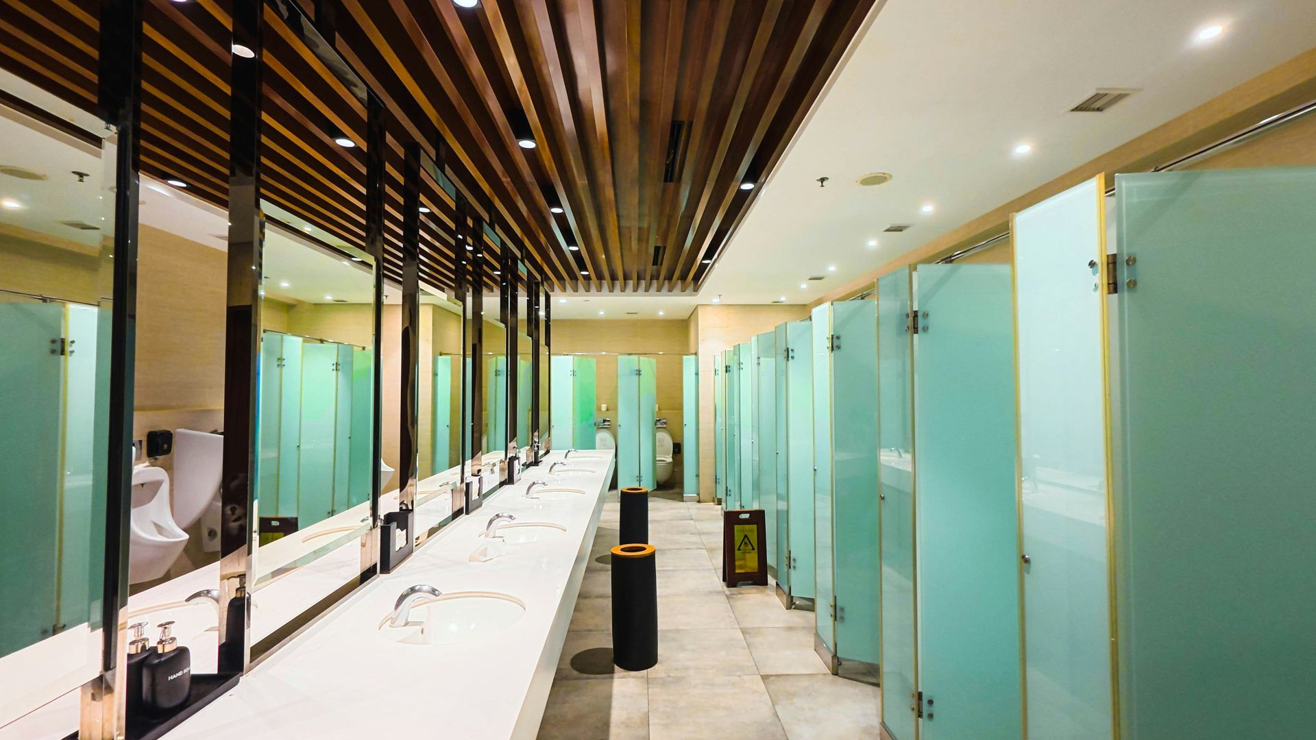 Modern public restroom with sinks, mirrors, and frosted glass stalls